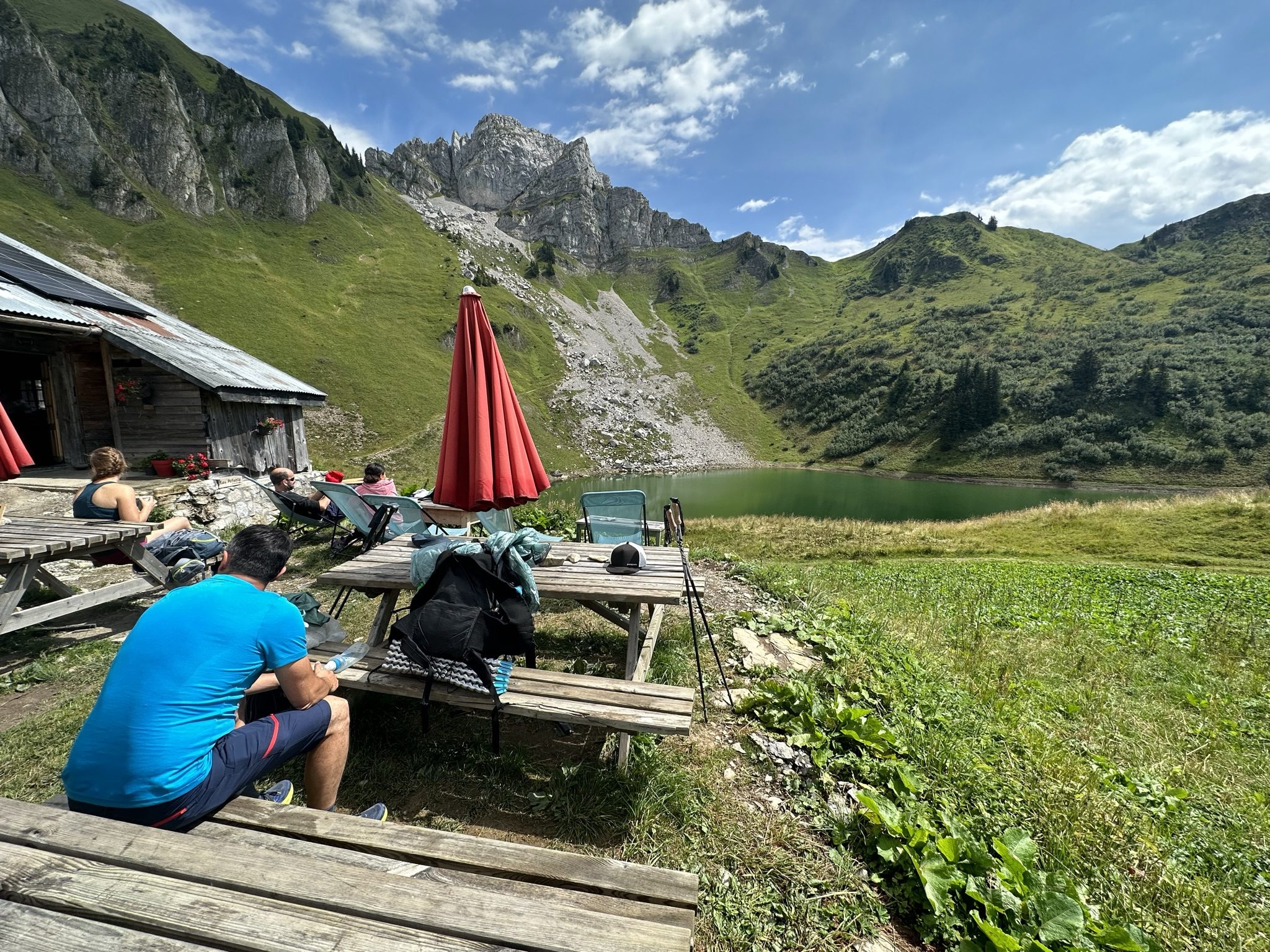 Randonneurs à la terrasse d un refuge alpin devant un lac