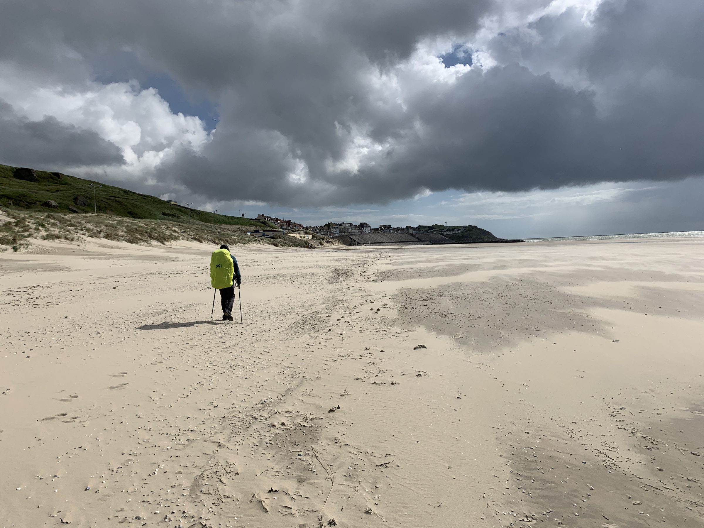 Randonneur seul sur une immense plage de sable sous les nuages
